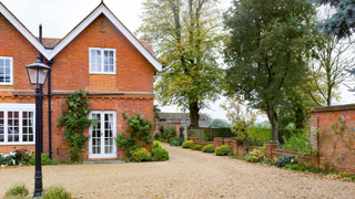 House with a gravel driveway and lamp to the left