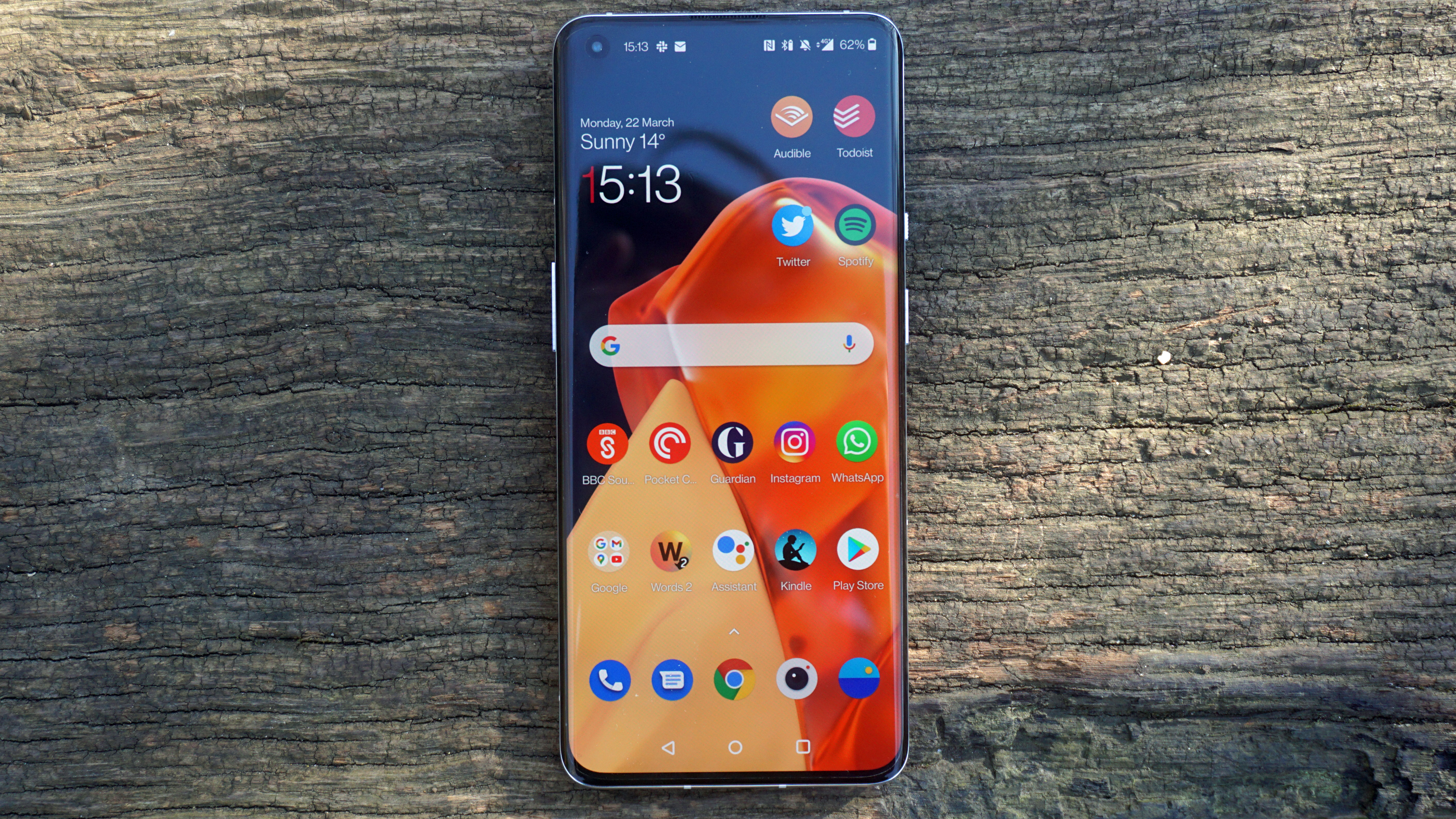 A OnePlus 9 Pro with the screen on against a wooden background