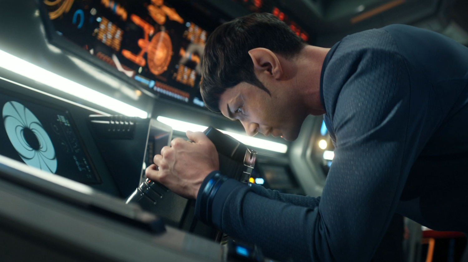 Spock looks through a scanner on the Enterprise bridge.
