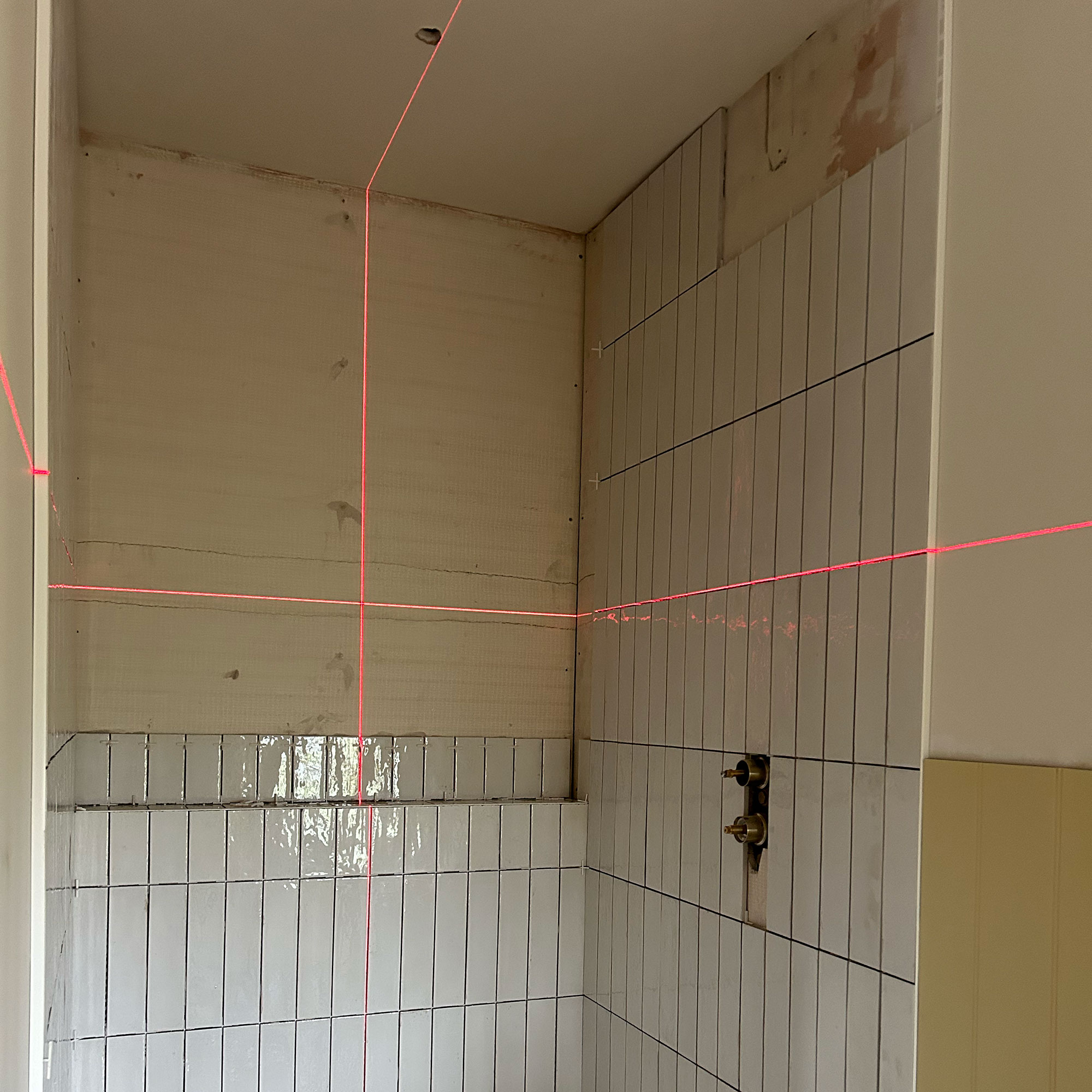 Laser level being used in bathroom mid-renovation