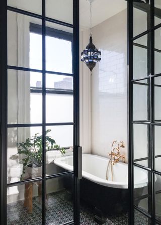 Bathroom with freestanding bath and crittall doors used as a room divider