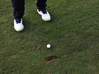 An image of a golf ball sitting on the fairway nex to an unrepaired divot