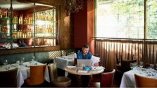 A restaurant owner sits in his empty restaurant while he looks over paperwork.