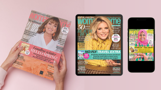 A pair of hands holding a woman&home magazine featuring Lorraine Kelly, beside a tablet showing a digital issue with Emilia Fox, and a phone showing the Nadiya Hussain issue