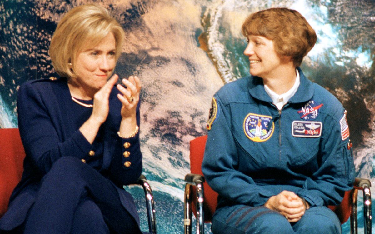 Hillary Clinton applauds now-retired NASA astronaut Eileen Collins, the first woman to command and pilot the space shuttle, during an outreach event at Dunbar High School in Washington, D.C., on March 5, 1998.