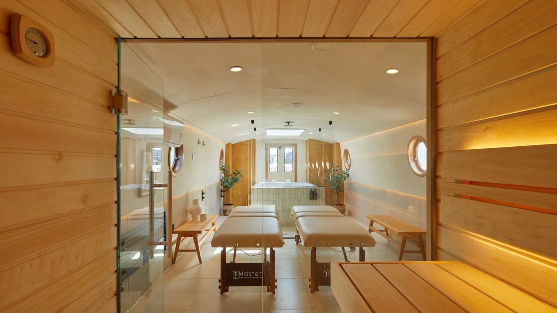 an image of the interior of the floating spa showing the wood saunda, treatment beds, and hot tub