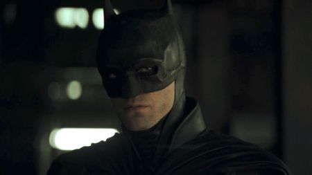 The Dark Knight (Robert Pattinson) stares ahead at Catwoman and more while listening to a recording in The Batman.