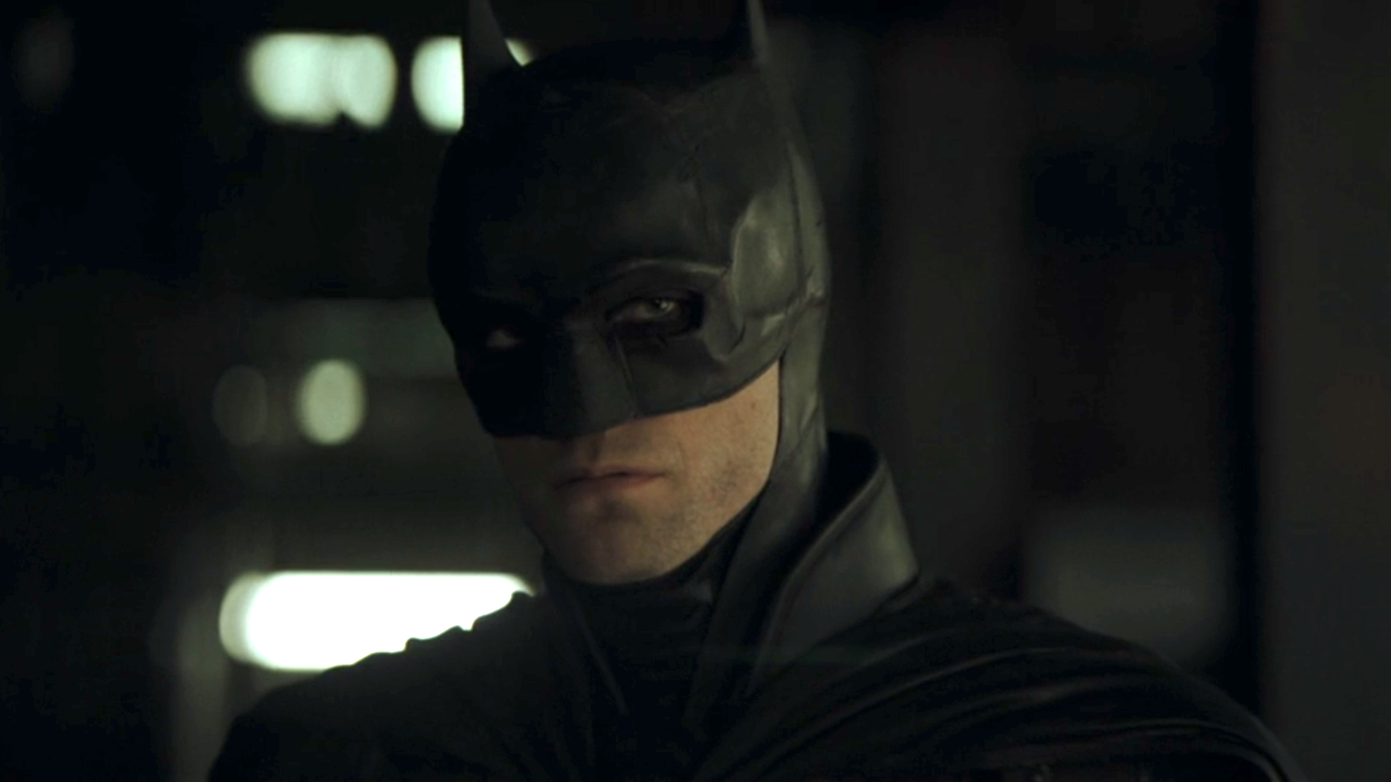 The Dark Knight (Robert Pattinson) stares ahead at Catwoman and more while listening to a recording in The Batman.