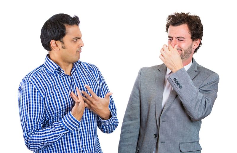 man looking at guy closing, covering nose, something stinks