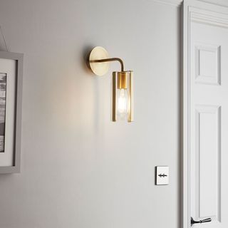 A grey wall and white door with gold wall light