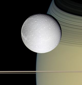 Dione in front of Saturn: Cassini's wide-angle camera shot three images — through blue, green and infrared filters — as the spacecraft flew 24,200 miles (39,000 km) from the moon to produce this photo.