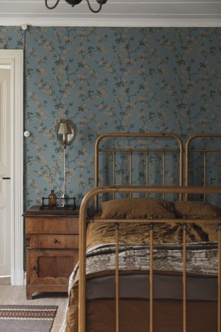 A bedroom with a bright patterned wallpaper