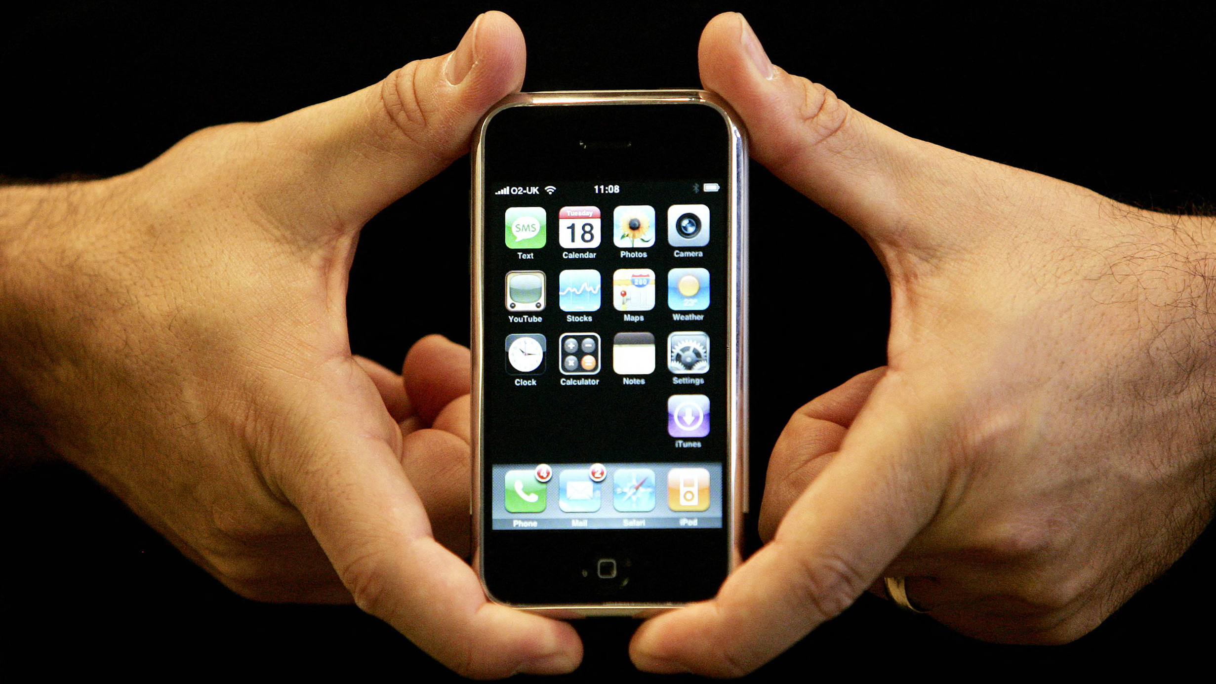 Two hands holding the first iPhone