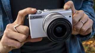 Image shows the Canon EOS M200 camera in someone's hands.