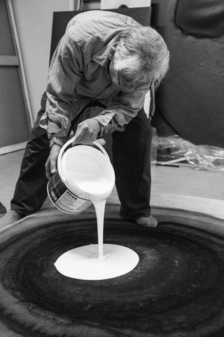 Portrait of Japanese artist Takesada Matsutani in the studio pouring vinyl glue onto a work in 2019 ahead of an exhibition at Hauser & Wirth Hong Kong. Photographer Michel Lunardelli
