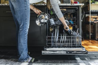Person putting kitchen utensils in a dishwasher