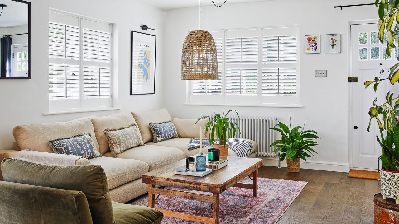 White living room with light coloured sofa, wooden coffee table, and colourful rug