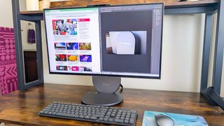 Lenovo Yoga AIO 27" sitting on a desk with the display split between displaying the Windows Central home page on the left and Adobe Photoshop on the right. 
