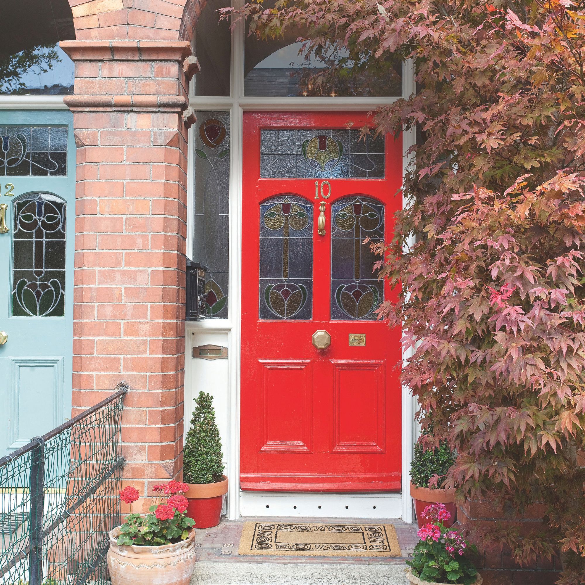 Exterior house with a red front door and a red bush to the side of it