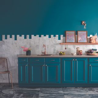 A kitchen with walls and cabinets painted in a teal blue