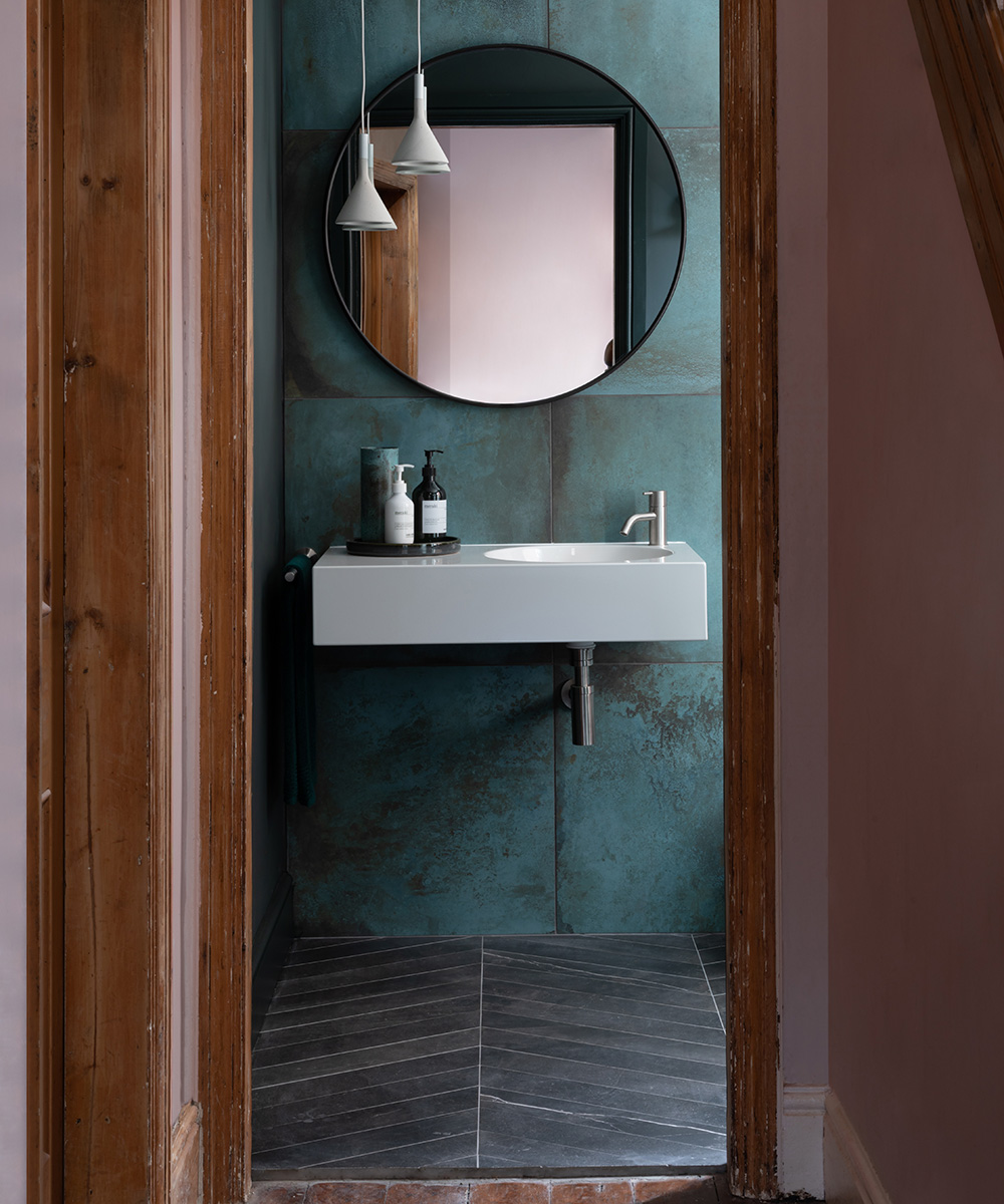 A dark bathroom with a large round mirror