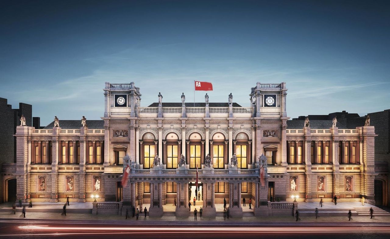 A grand two-storey building with 2 clock towers and many tall windows with semi-circle crowns