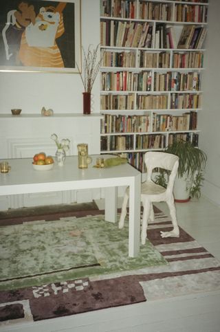 Dining table with colourful rug and bookcase