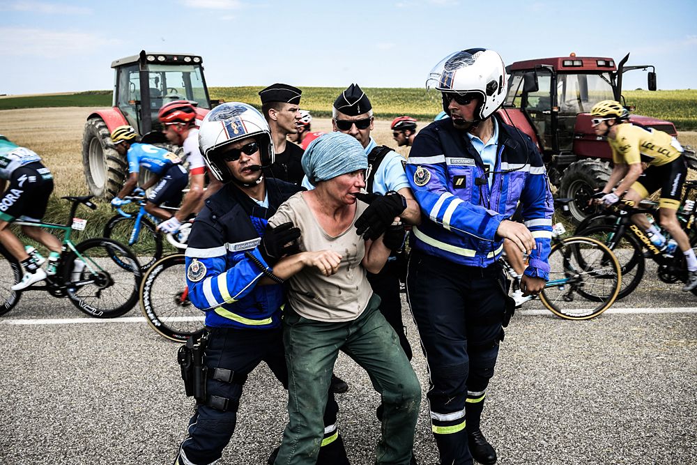Gendarmes detain a protester during a farmers' protest who attempted to block the stage's route, during the 16th stage of the 105th edition of the Tour de France