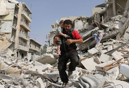 A man carries a baby out of a destroyed building in Aleppo