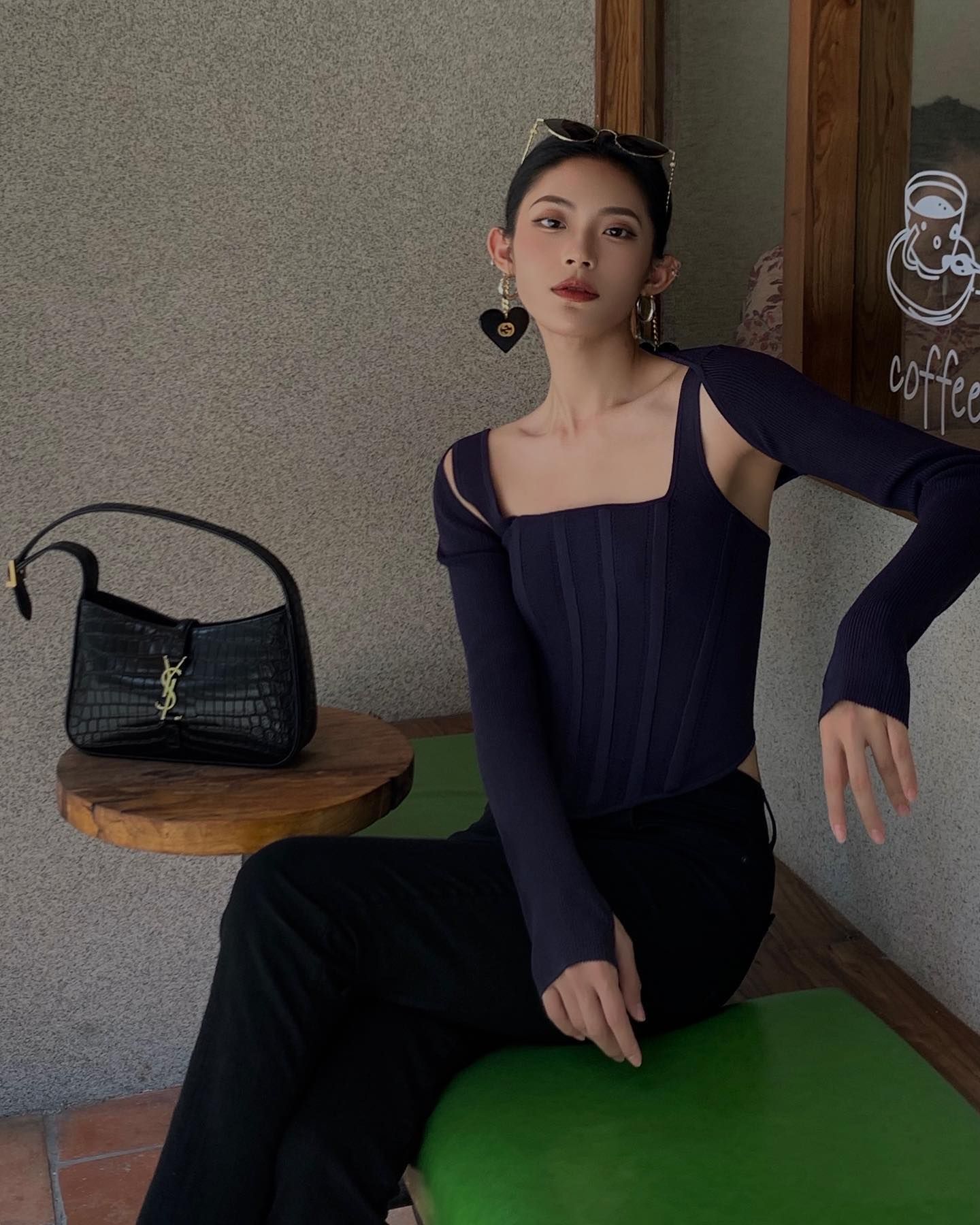 Woman wears denim top, black trousers and has ysl bag on table