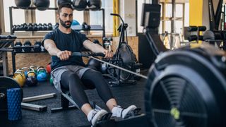 Man using indoor rowing machine in gym