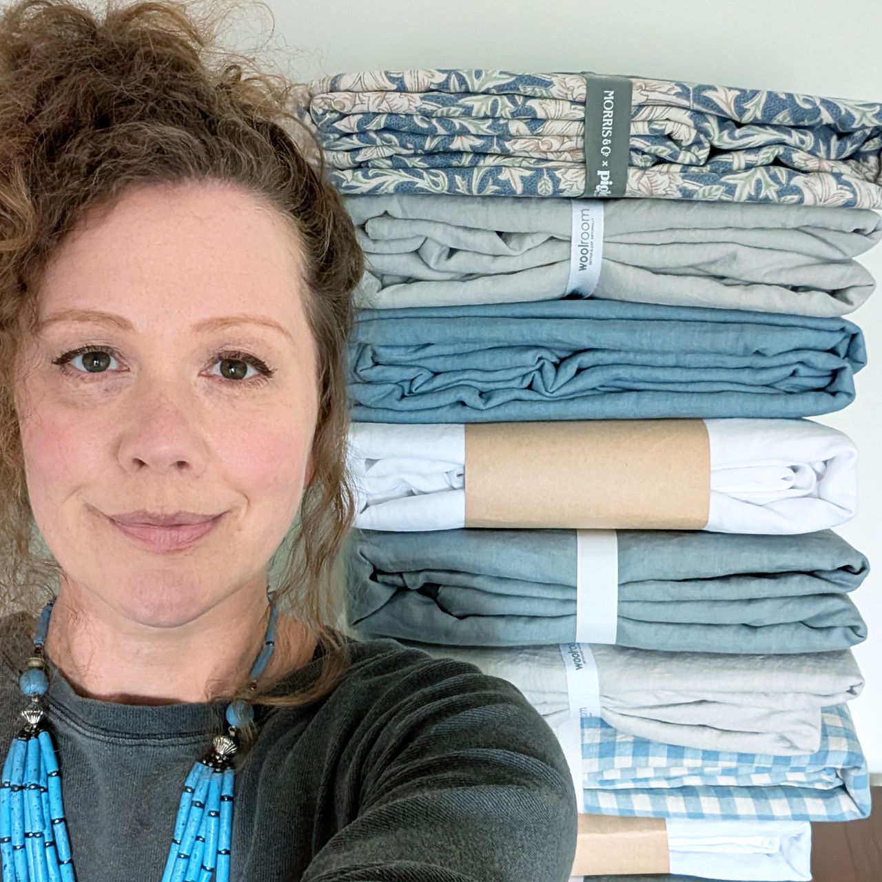 Amy - Ideal Home's Sleep Editor, in front of a pile of linen bedding
