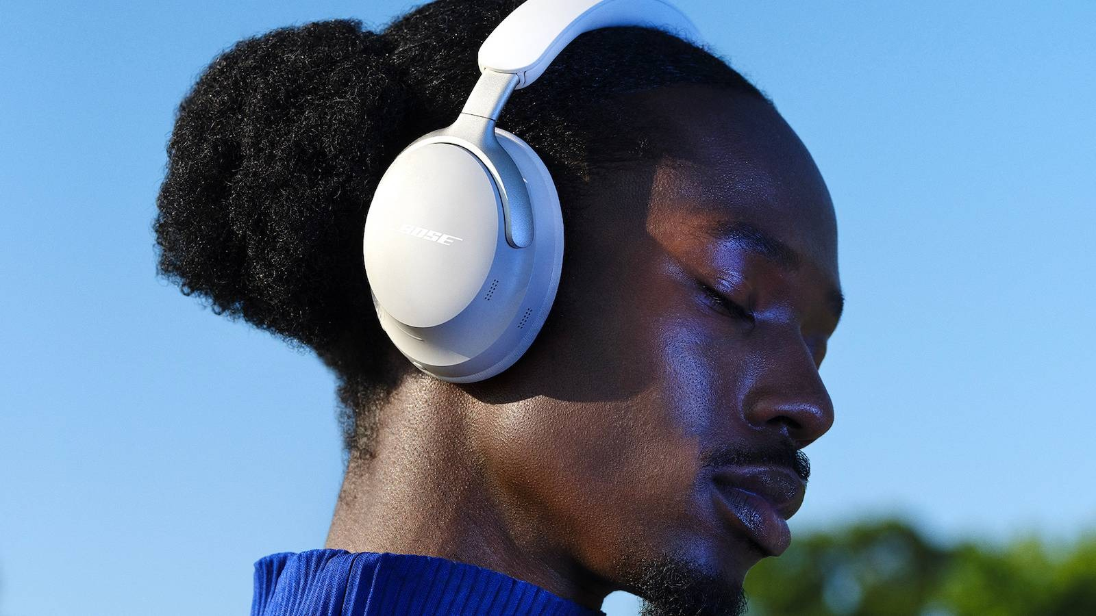 Man with eyes closed wearing white Bose QuietComfort Ultra headphones