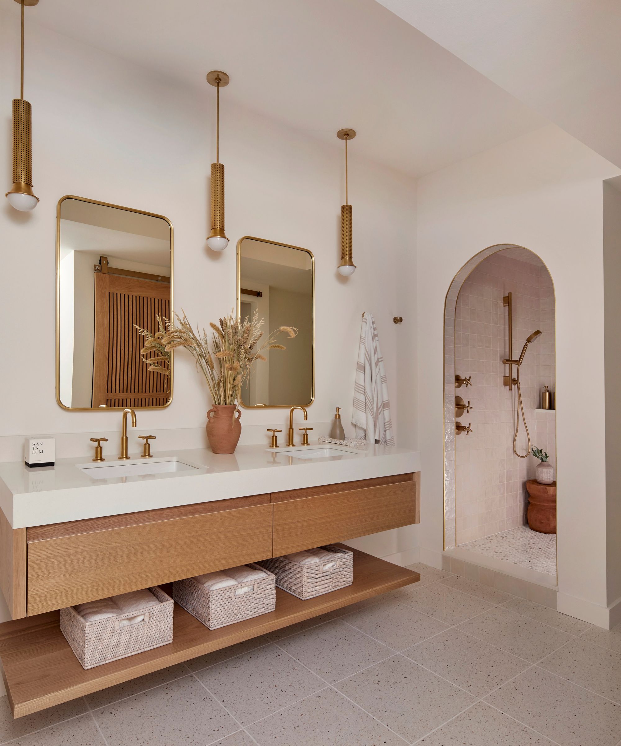 A bathroom painted in Benjamin Moore Simply White paired with a wooden vanity and gold accents