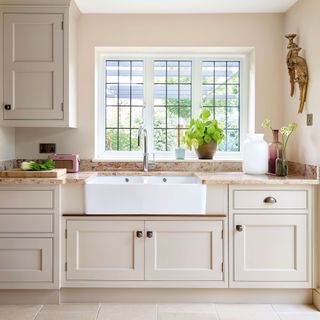 kitchen with cream cabinetry and butler sink in front of a window