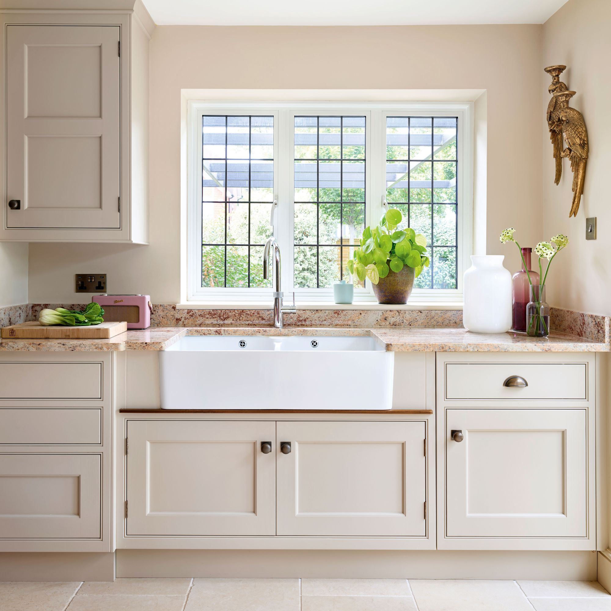 kitchen with cream cabinetry and butler sink in front of a window