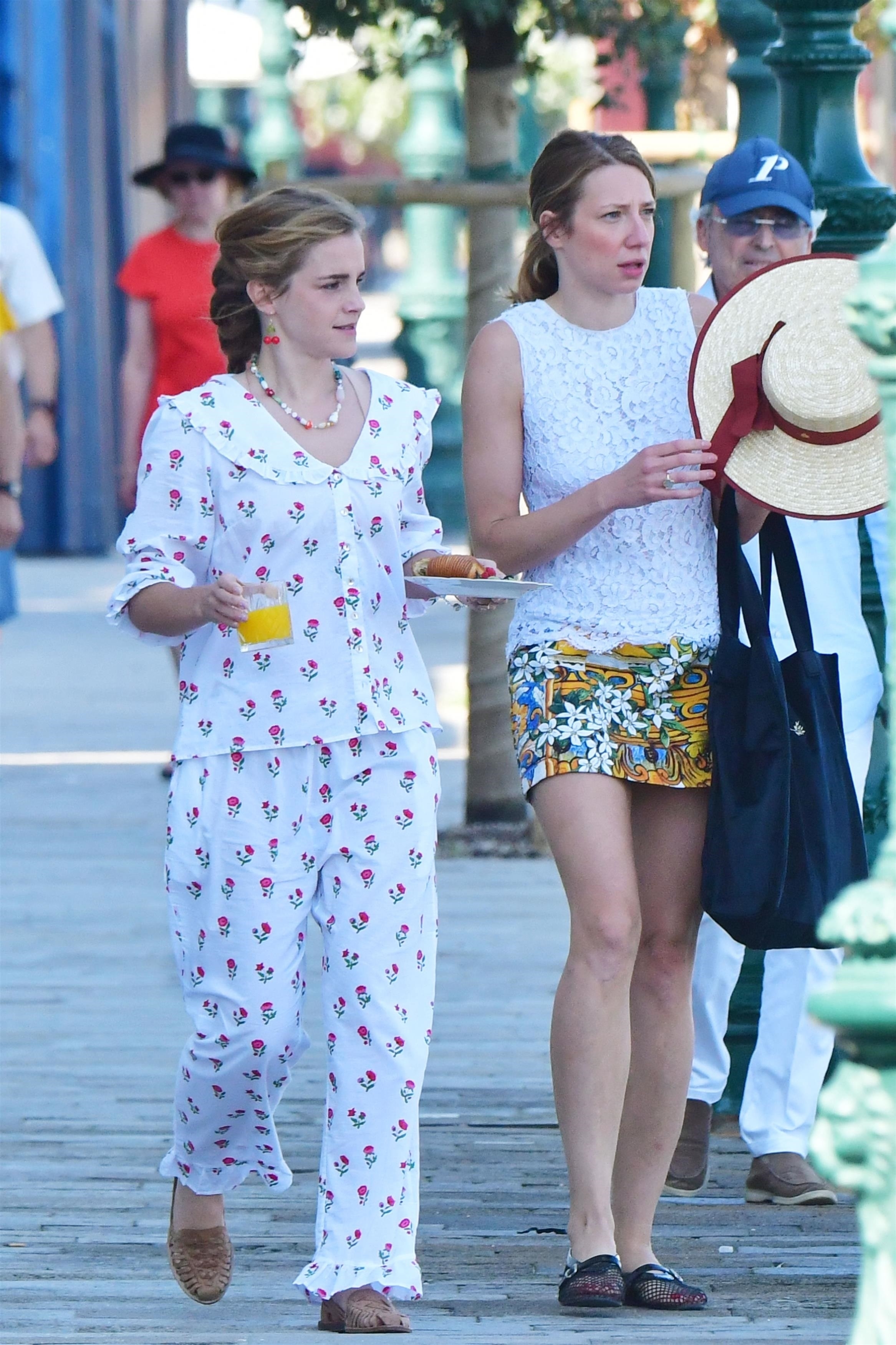 Emma Watson wears woven loafers with a matching floral cotton set. She's holding and orange juice and a plate with a croissant.