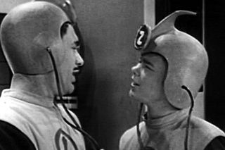 Two men in weird retro sci-fi outfits and helmets