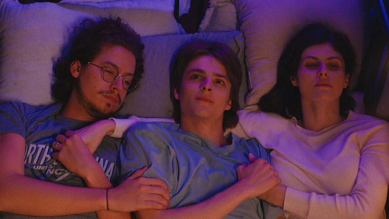 Cole Sprouse, Corey Fogelmanis, Alexandra Daddario laying in bed together in I Wish You All The Best