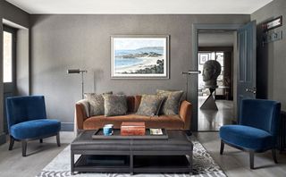 Contemporary gray living room with sofa and blue velvet armchairs arranged around a large coffee table