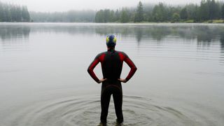 Man getting ready to go swimming in a wetsuit