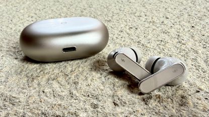 The Huawei FreeBuds Pro 5 pictured on a stone surface alongside their charging case