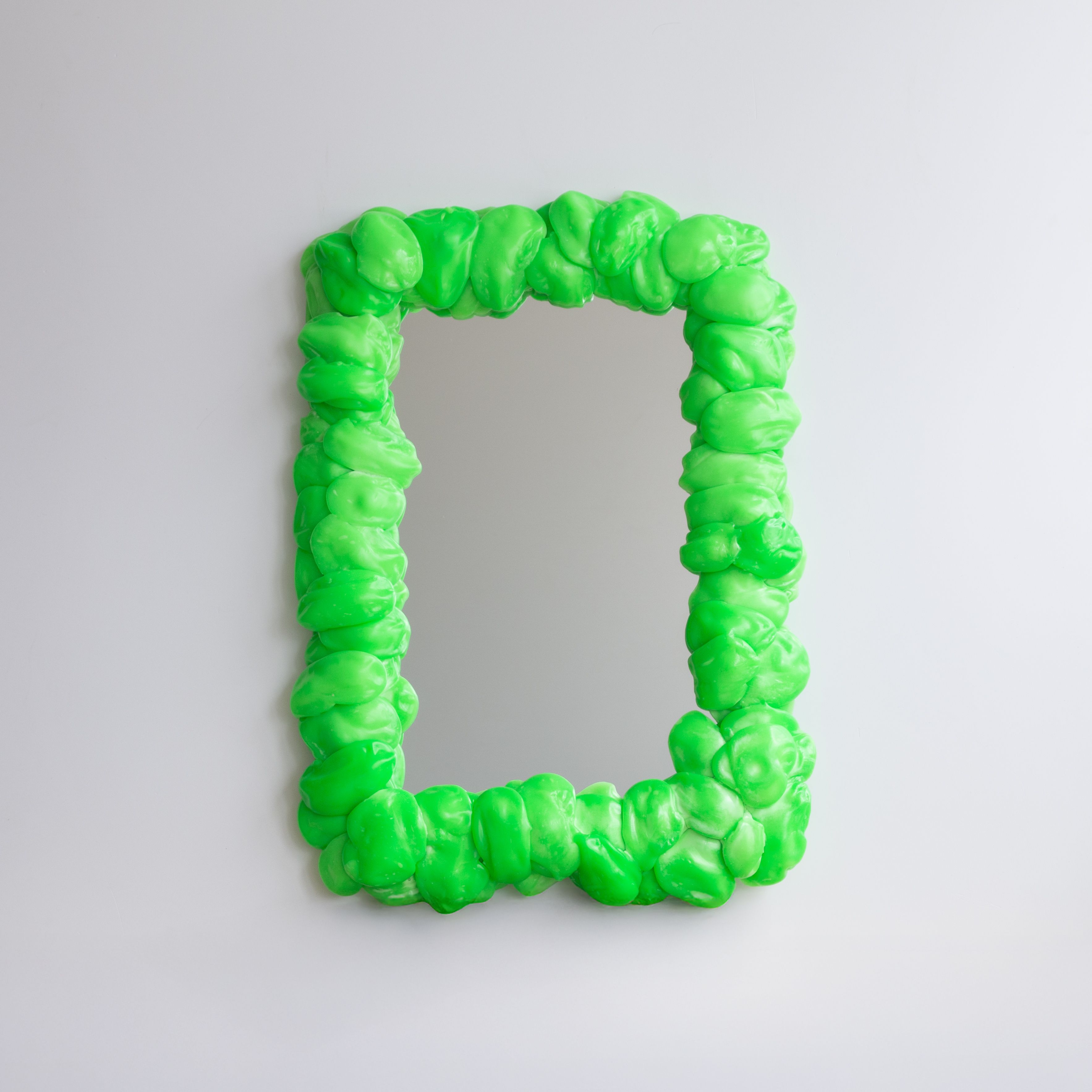 A series of squishy home objects designed from melted plastic and chrome or brass detailing, including a mirror, candelabra, and a kitchen towel rack.