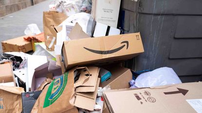 A broken Amazon box tossed in with other trash