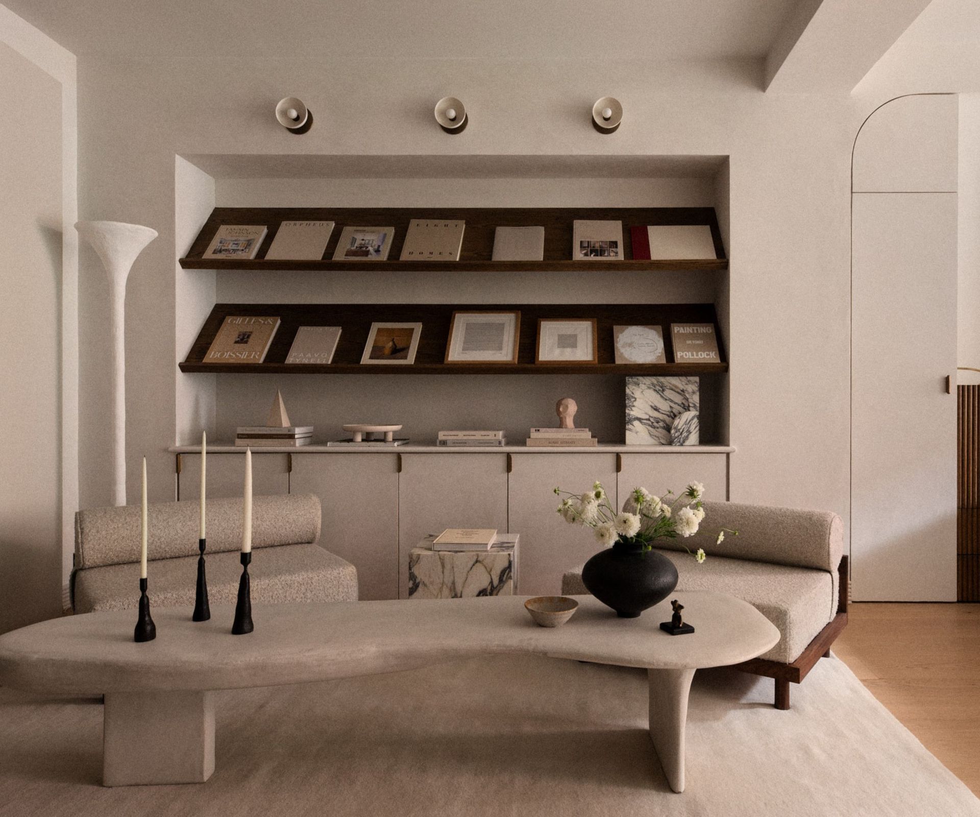 Minimal style living room with boucle chairs, stone abstract table, candles and vase with flowers