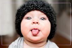 Baby wearing a hat and poking out its tongue