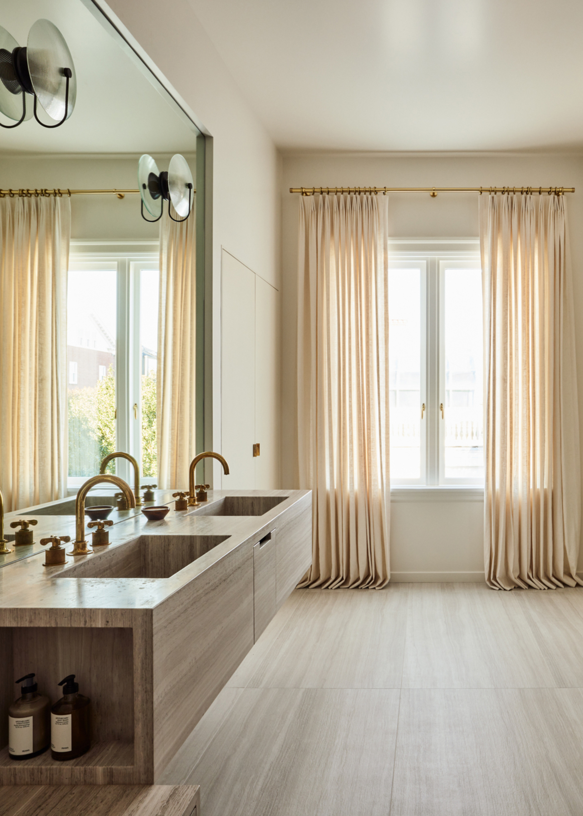 A bathroom with soft curtains and a double sink as well as a large mirror in the space