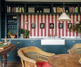 Red and white stiped wallpaper, blue cabinets and drawers, wicker chair
