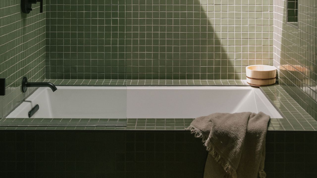 tiled green walls and bathtub with black fixtures