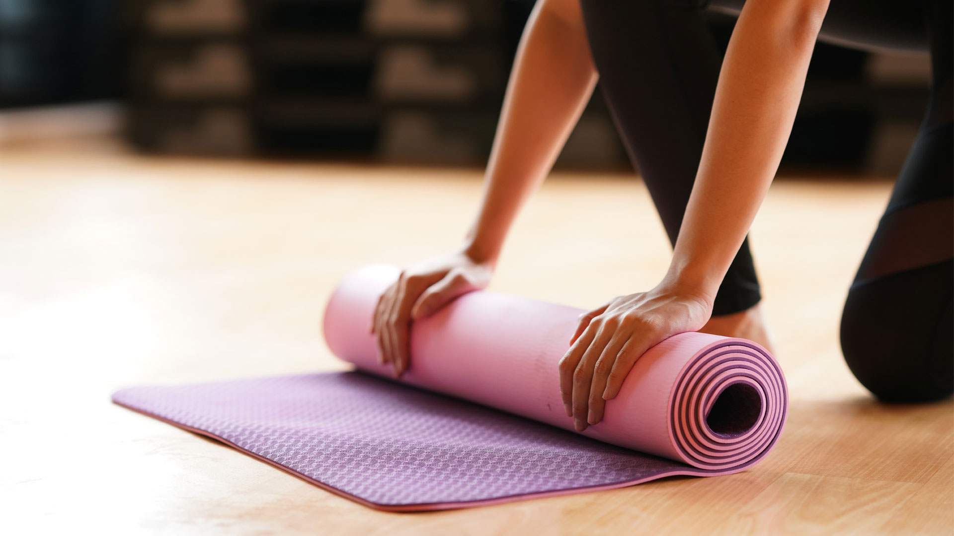 Yoga bei Rückenschmerzen: Bild zeigt Person, die Yogamatte rollt